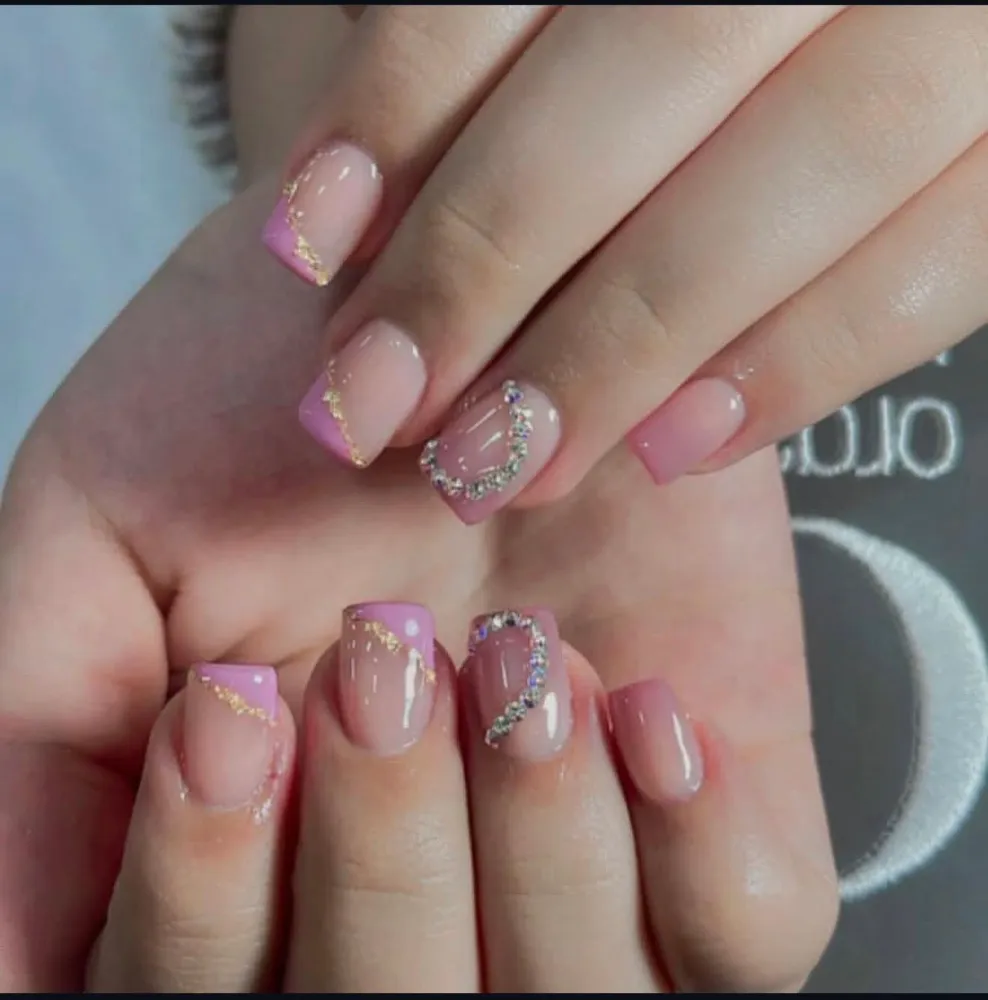 Diseño de uñas rosa con detalles dorados y pedrería